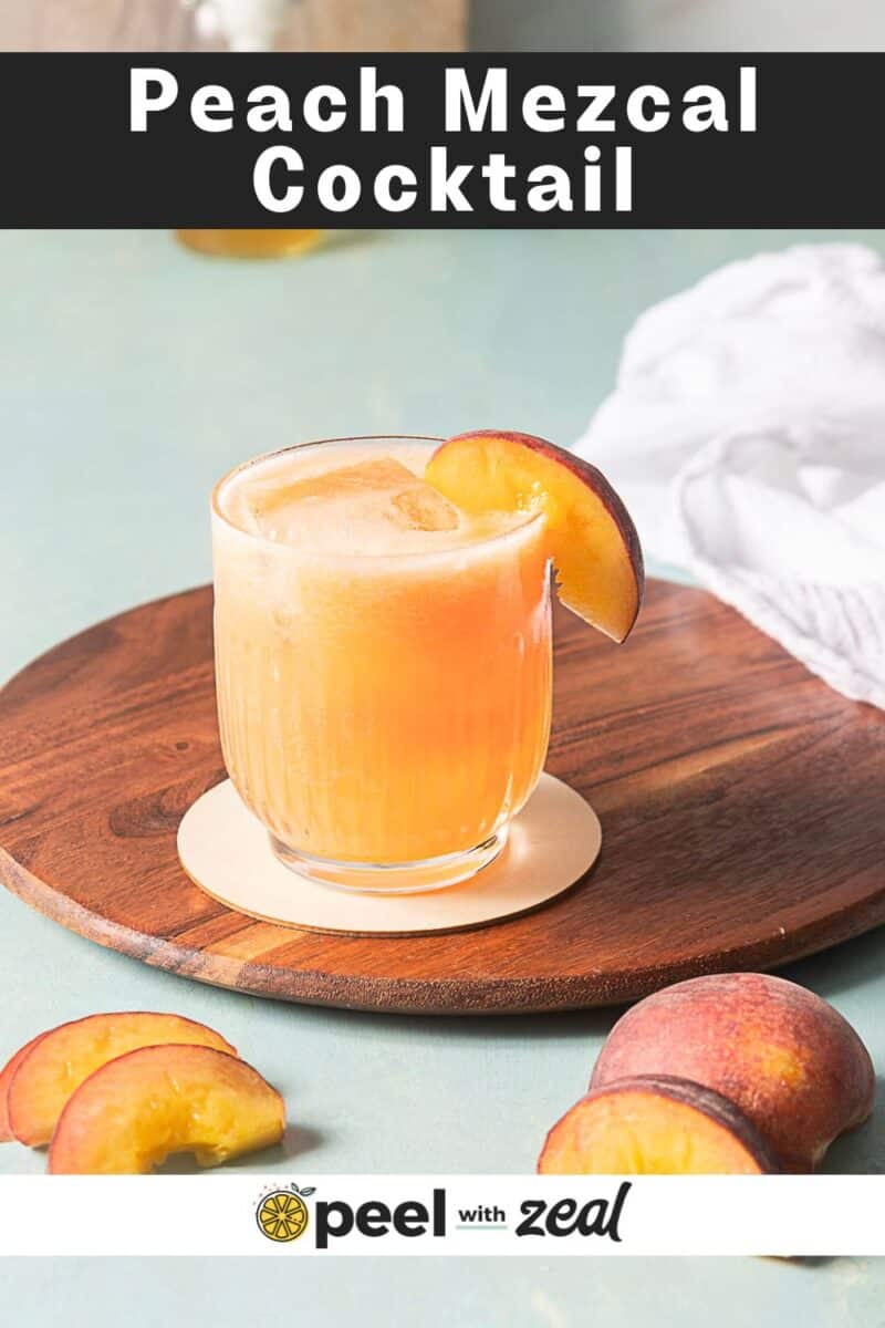 A glass of peach mezcal cocktail with ice, garnished with a peach slice, sits on a wooden board with fresh peach slices nearby. The text reads "Peach Mezcal Cocktail.