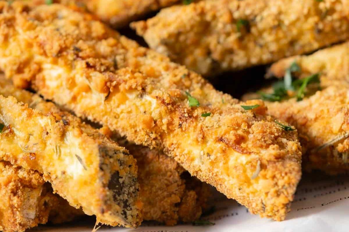 Close-up of crispy, breaded zucchini fries garnished with herbs, arranged on a plate-perfect inspiration for those seeking new takes on classic veggie sides or exploring eggplant recipes and cooking eggplant at home.
