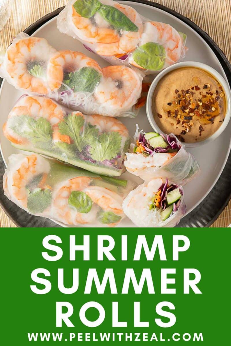 A plate of fresh shrimp summer rolls with mixed vegetables, served alongside a bowl of dipping sauce.