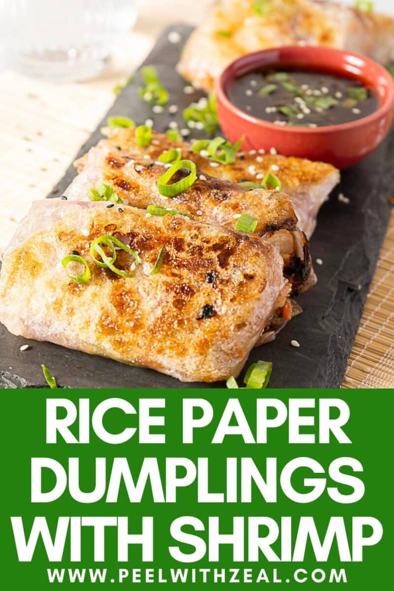 Grilled rice paper dumplings filled with shrimp, topped with sliced green onions, and served with a side of dipping sauce on a slate platter.