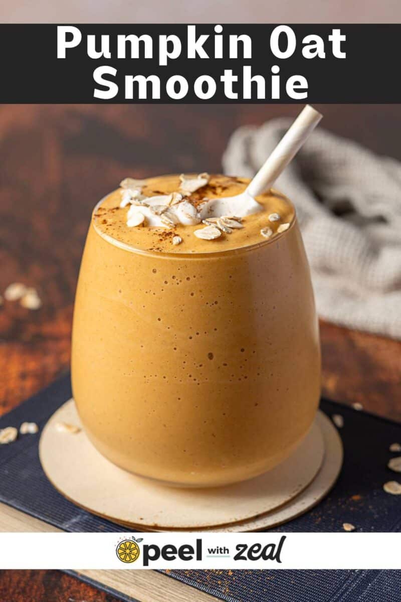 A glass of pumpkin smoothie with oats and a sprinkle of cinnamon sits on a coaster, a straw ready for sipping and scattered oats nearby.