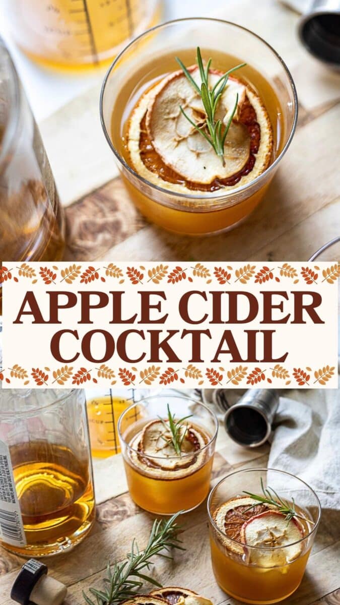 Two glasses of bourbon apple cider cocktail garnished with dried apple slices and rosemary sit on a wooden surface, surrounded by bottles and a jigger.