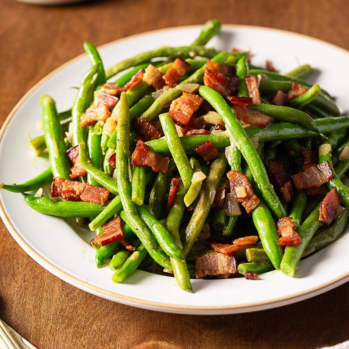 fresh green beans with bacon in a white plate