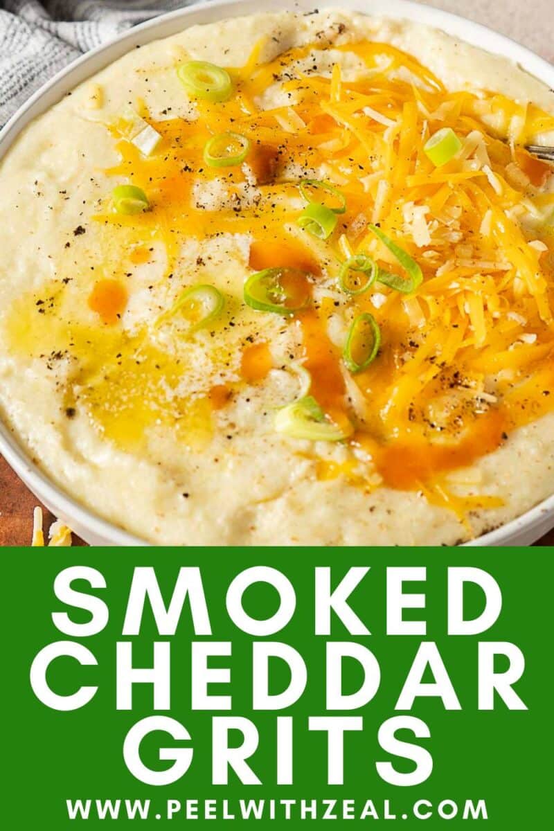 Bowl of creamy cheddar grits topped with shredded cheese, sliced green onions, black pepper, and a splash of hot sauce.