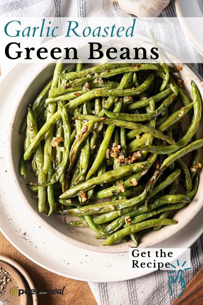 A bowl of garlic roasted green beans garnished with minced garlic sits on a wooden surface, with text overlay highlighting this delicious garlic roasted green beans recipe.