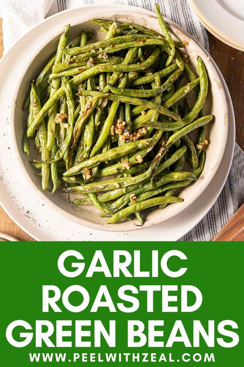 A plate of garlic roasted green beans on a beige dish, garnished with minced garlic.