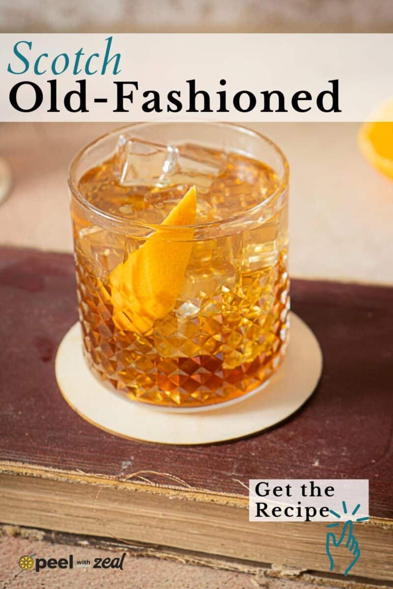 A glass of Scotch Old-Fashioned with ice and an orange twist sits on a white coaster atop a book, highlighting the classic scotch old fashioned. "Get the Recipe" text appears in the corner.