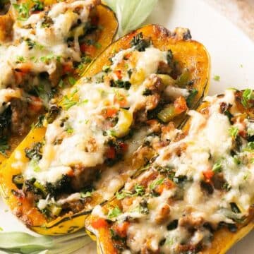 Three halves of stuffed squash filled with a mixture of vegetables, ground meat, and topped with melted cheese on a white plate—perfect for those seeking easy squash recipes.