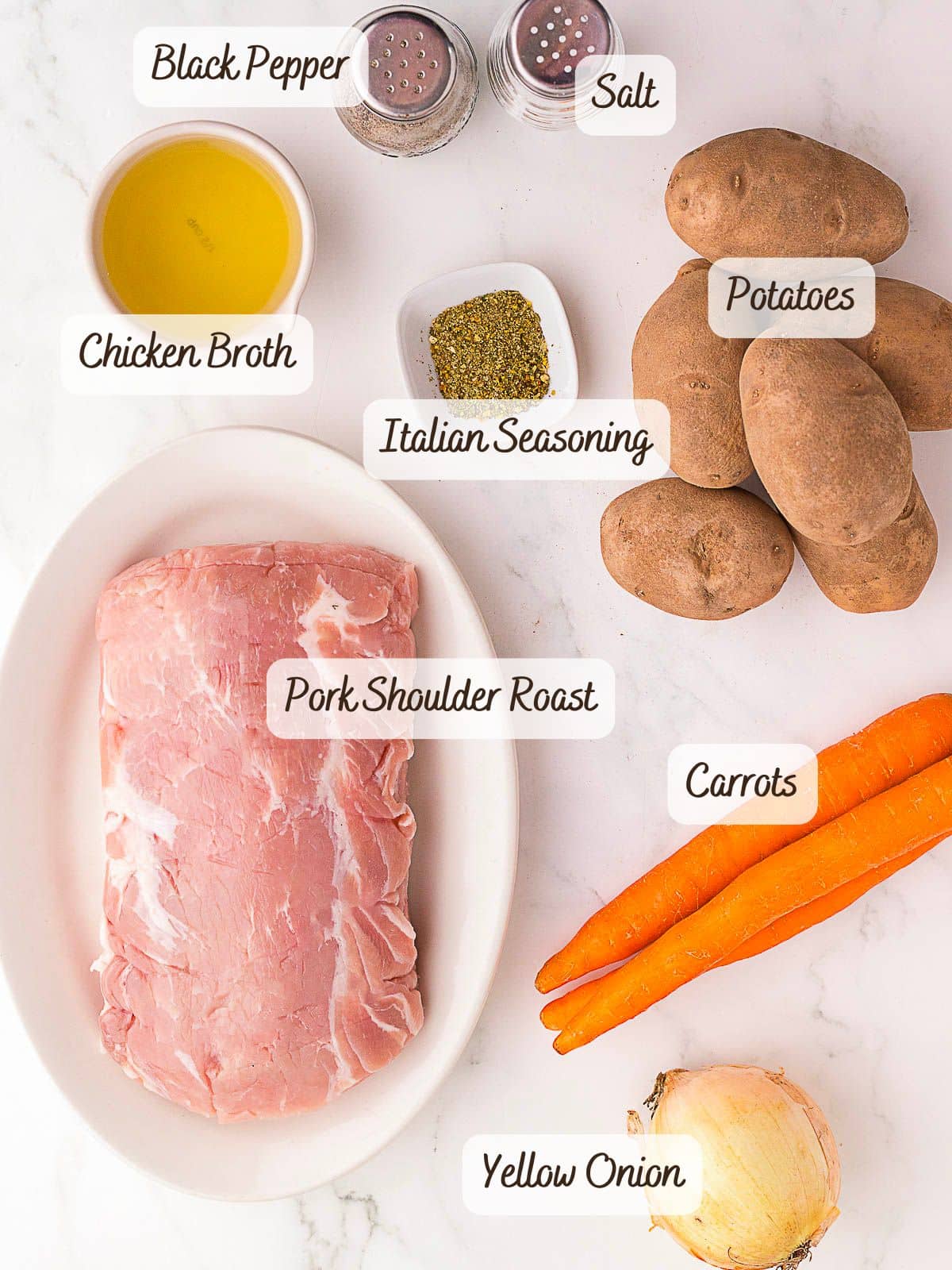 Ingredients for a slow cooker pork roast meal, including pork shoulder roast, carrots, yellow onion, potatoes, chicken broth, olive oil, Italian seasoning, salt, and black pepper.
