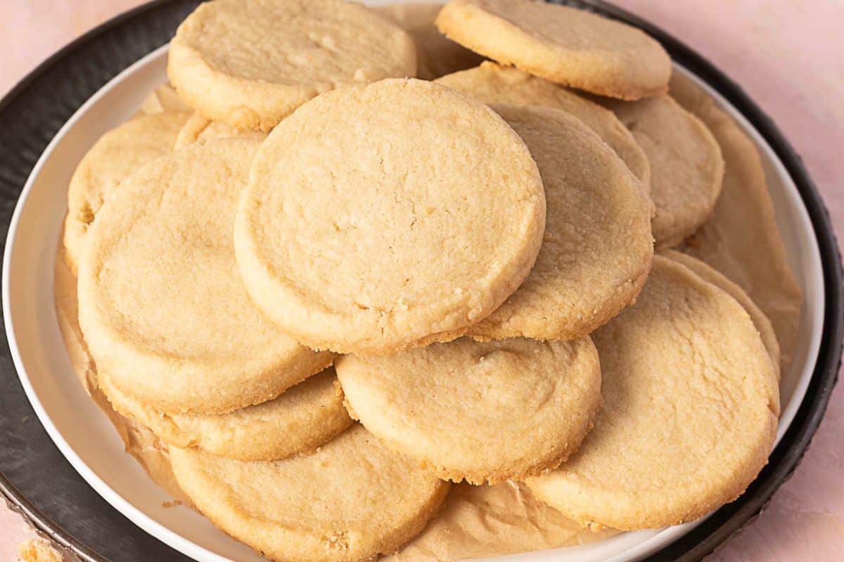 A plate of plain round shortbread cookies stacked on top of each other.