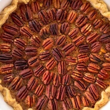 A baked pecan pie with a golden crust and pecan halves arranged in a circular pattern on top, perfect for those seeking gluten-free Thanksgiving desserts.