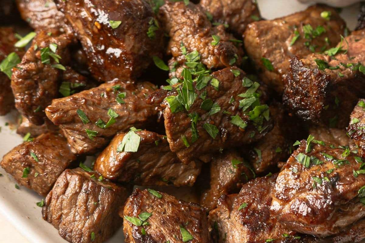 Close-up of cooked steak bites garnished with chopped parsley-perfect as holiday appetizers for your next gathering.