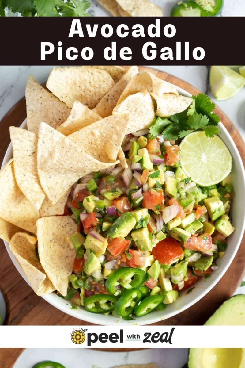 A bowl of avocado pico de gallo garnished with lime, jalapeño slices, cilantro, and served with tortilla chips.