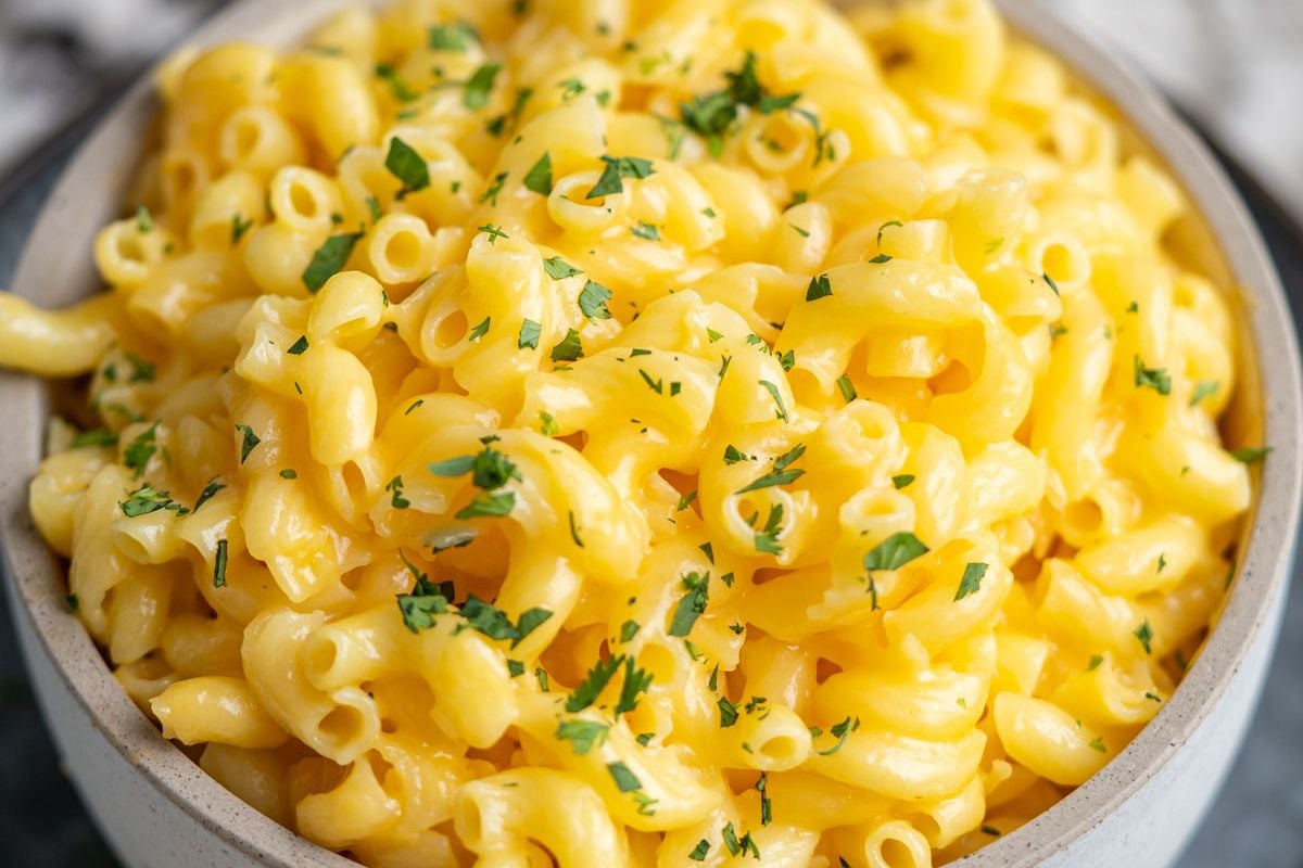 A bowl of macaroni and cheese topped with chopped parsley.