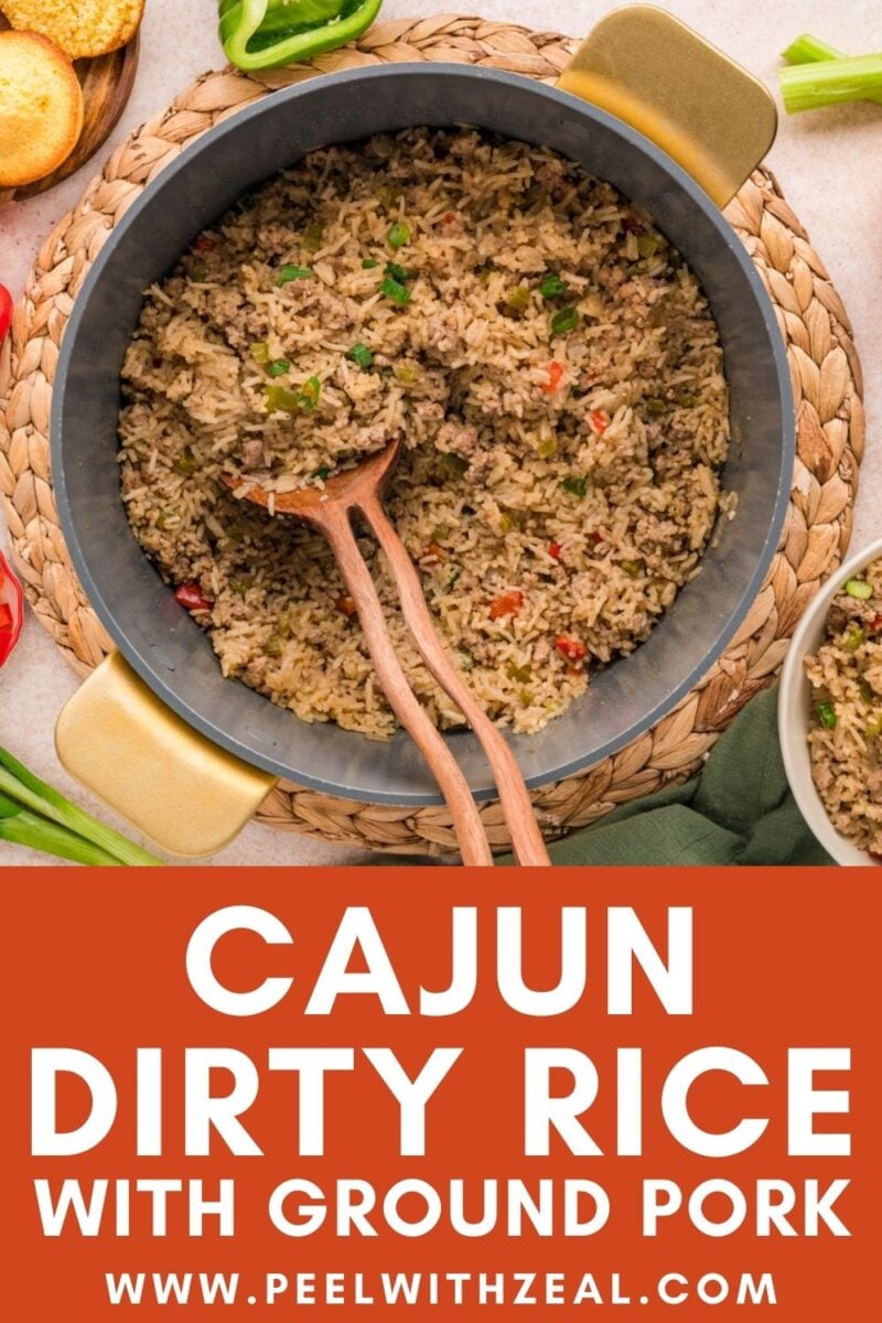 A pot of Cajun dirty rice with ground pork, mixed vegetables, and wooden serving utensils, shown from above with a portion served in a bowl.