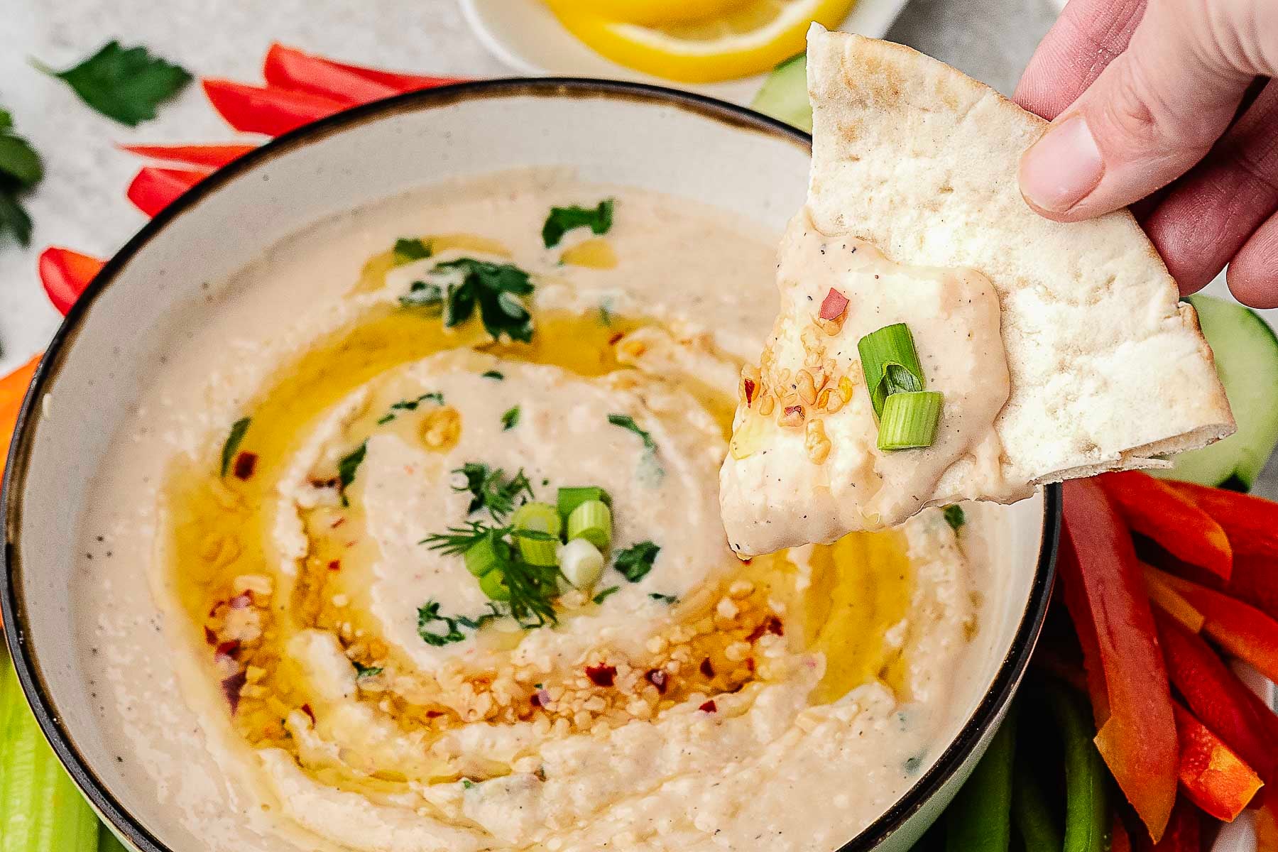 A chip dipped in a bowl of white bean dip.