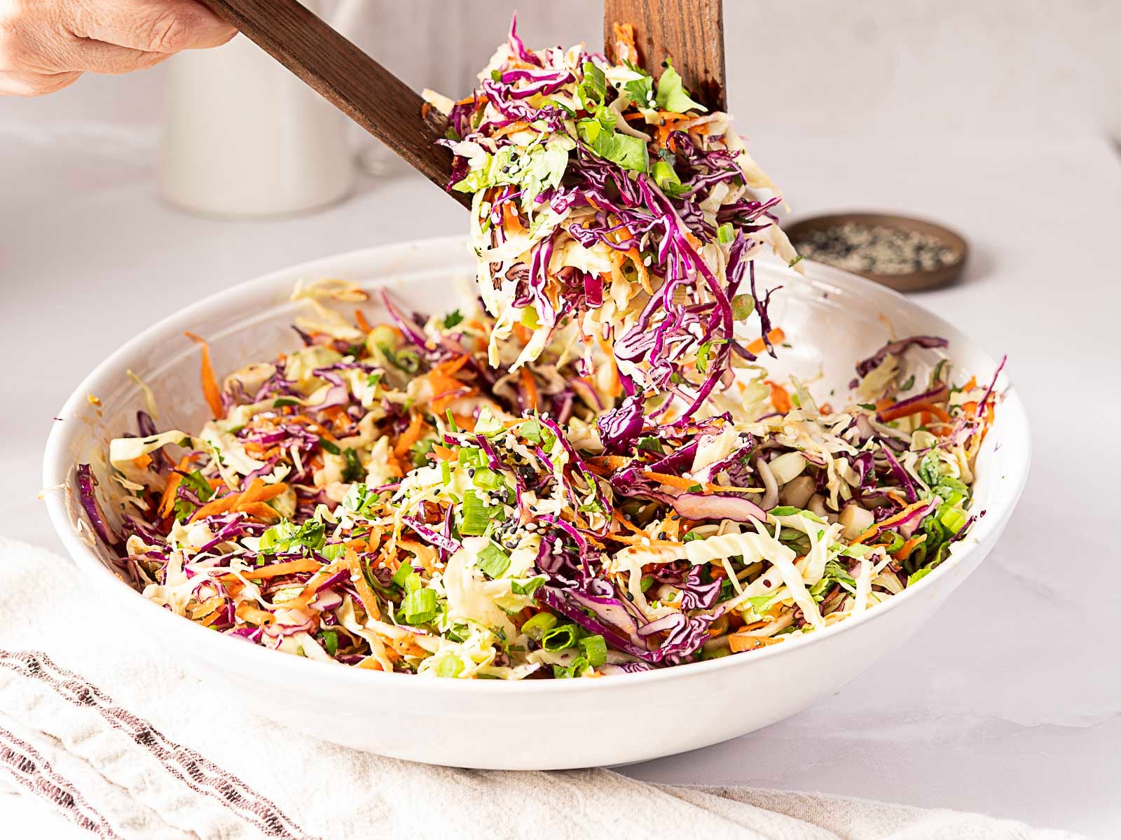 A bowl of Asian coleslaw beisng scooped. 