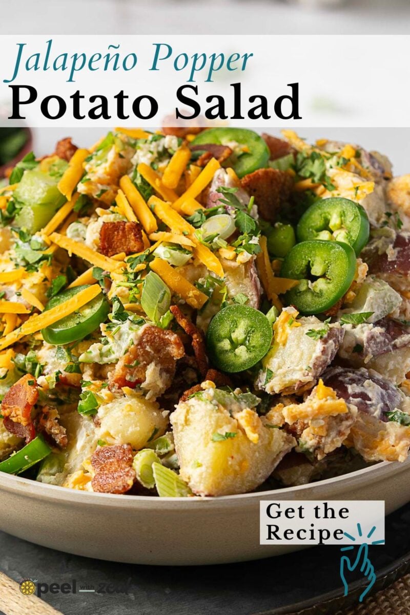 A bowl of jalapeno popper potato salad topped with sliced jalapeños, grated cheese, bacon, and green onions. Text reads "Jalapeño Popper Potato Salad" and "Get the Recipe.