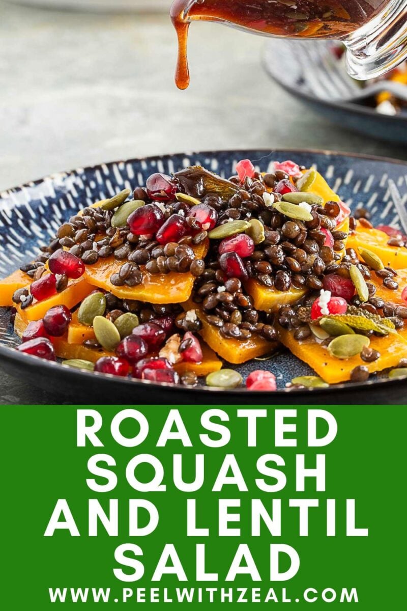 A plate of butternut squash salad with roasted lentils, pomegranate seeds, and pumpkin seeds, finished with a drizzle of dressing being poured over the top.
