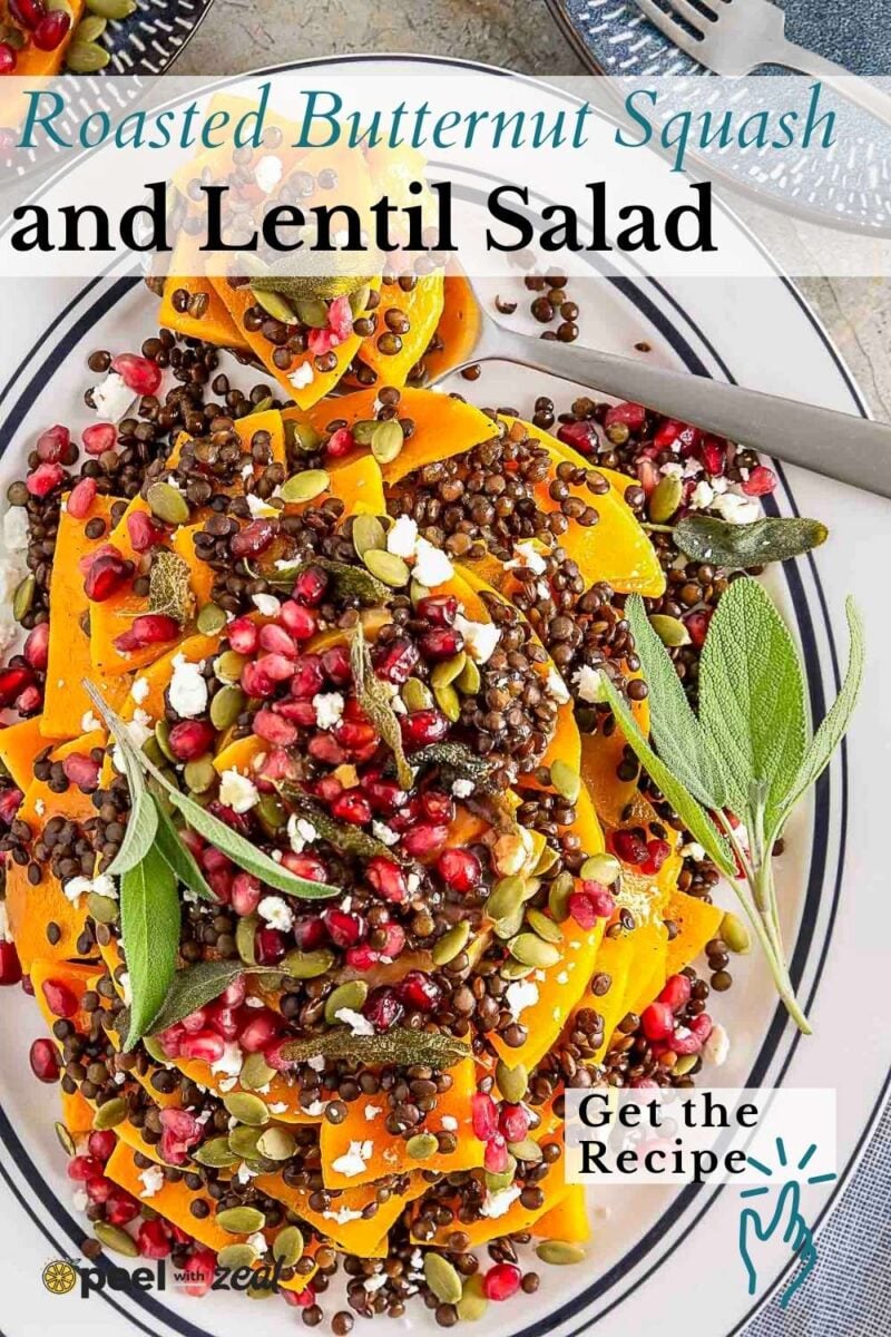 Plate of roasted butternut squash salad with lentils, topped with pomegranate seeds, pumpkin seeds, and fresh herbs, presented on a striped plate.
