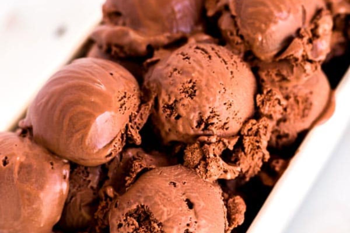 Several scoops of chocolate ice cream are closely arranged in a container, showcasing a creamy, rich texture.