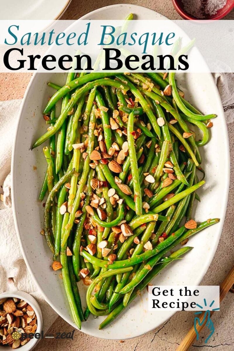 Oval dish of sautéed green beans topped with chopped nuts, photographed from above on a light background.