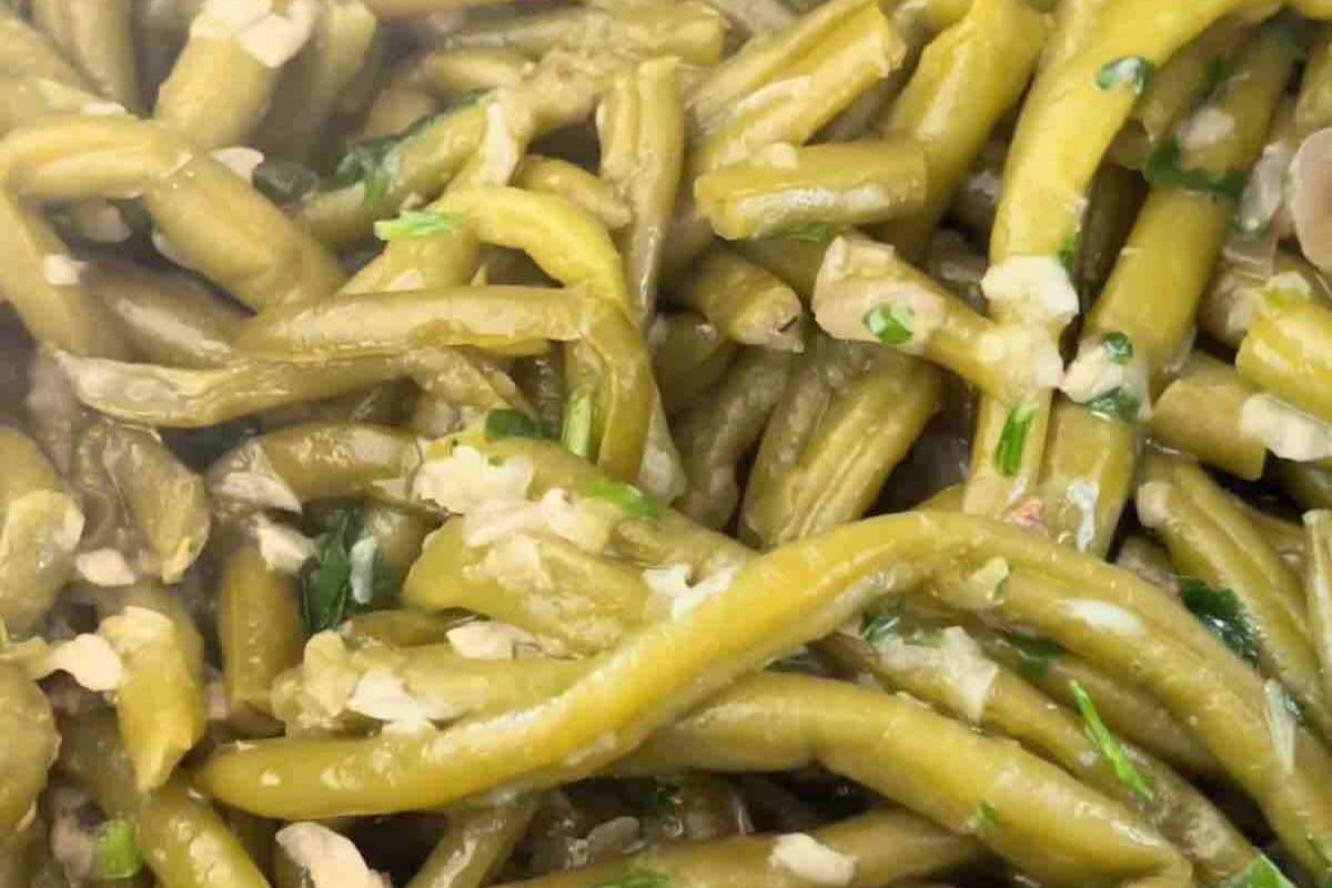 Close-up of cooked green beans mixed with chopped garlic and herbs.