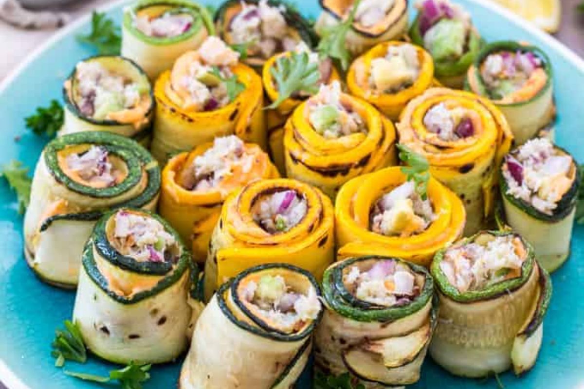 Plate of assorted zucchini and yellow squash rolls filled with salad mixture, garnished with fresh parsley.