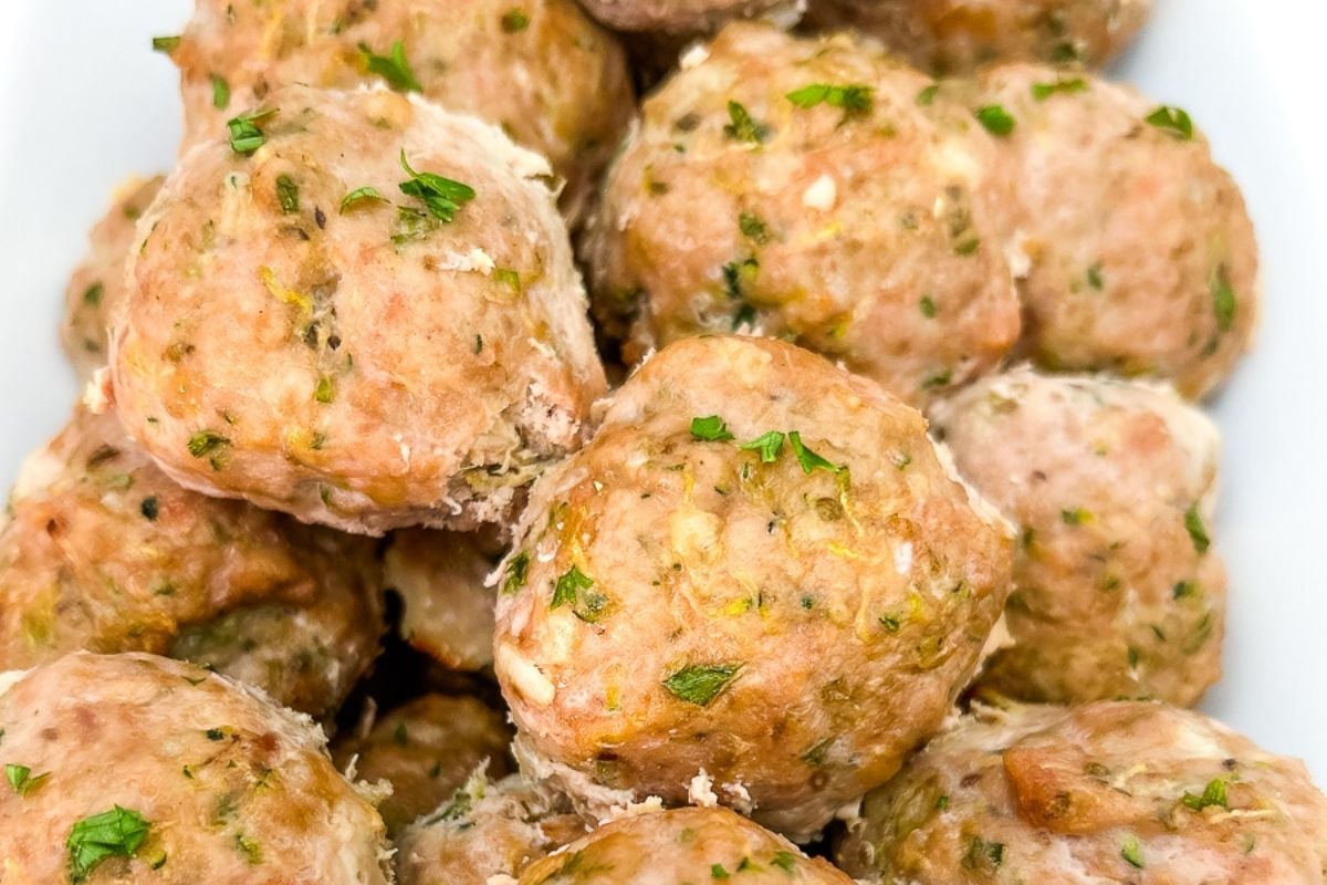 A close-up view of cooked turkey meatballs with visible herbs and seasonings, arranged in a white dish.