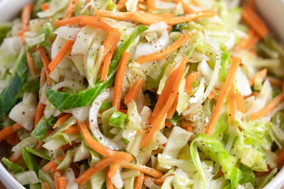 Close-up of shredded cabbage and carrot salad with visible black pepper seasoning—a classic addition to your collection of crowd-pleasing recipes.