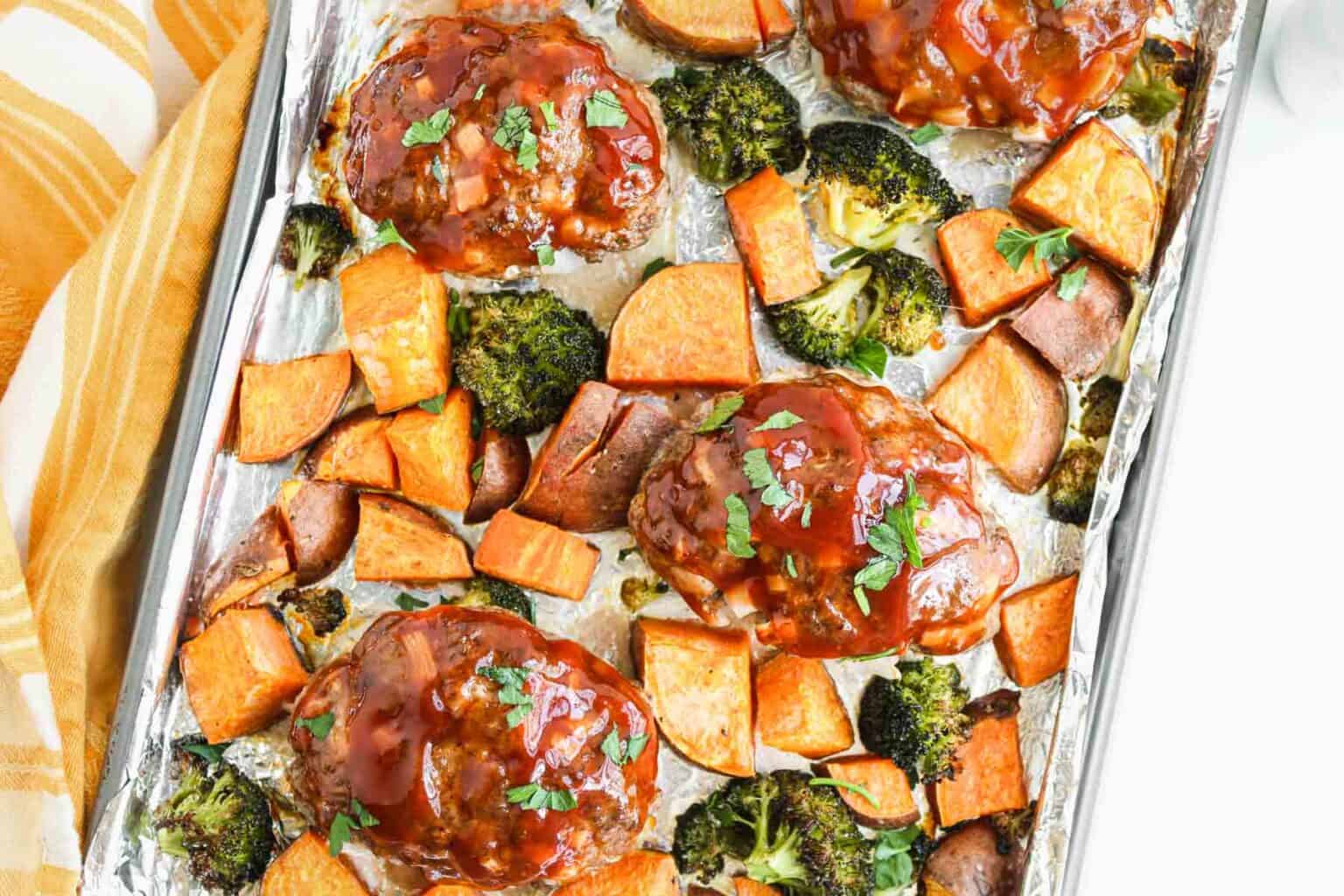 This sheet pan features four glazed mini meatloaves alongside roasted sweet potatoes, broccoli, and red potatoes on foil—perfect for Quick Dinners and effortless Sheet Pan Meals.