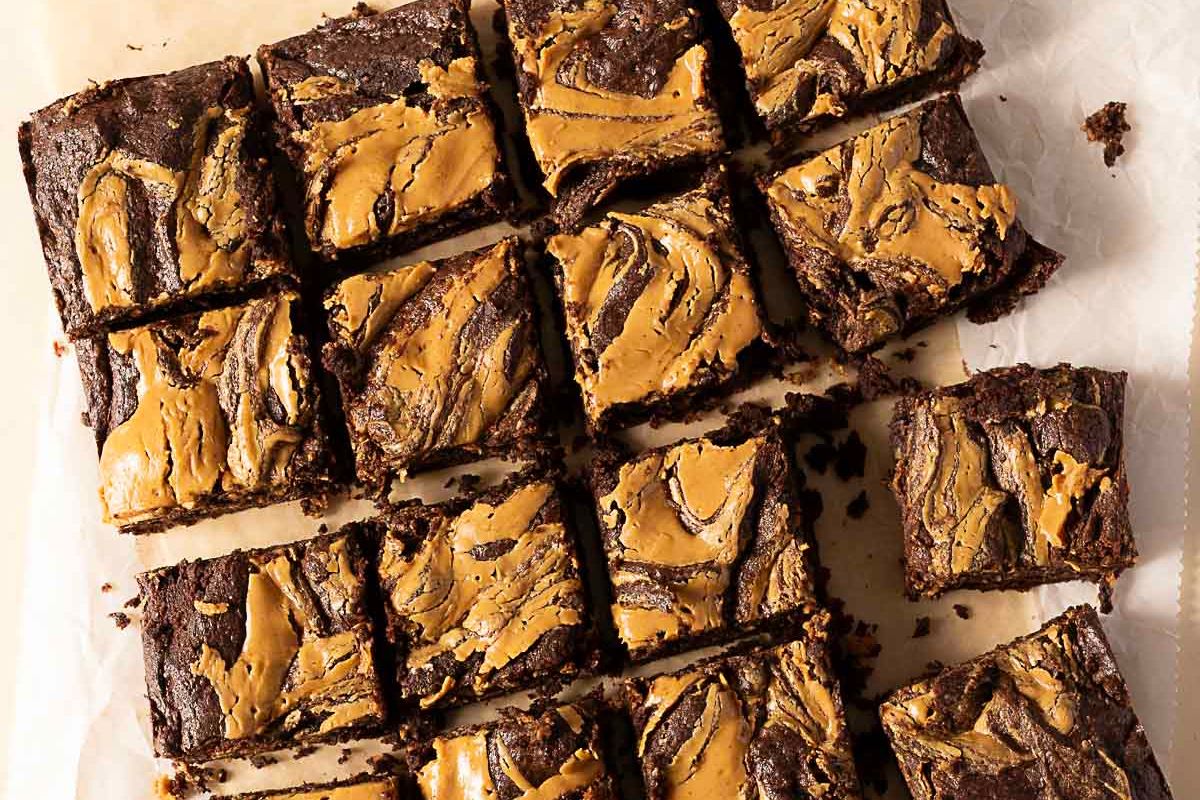 Sliced brownies with a peanut butter swirl pattern on top, arranged on parchment paper—a decadent addition to your collection of peanut butter desserts.