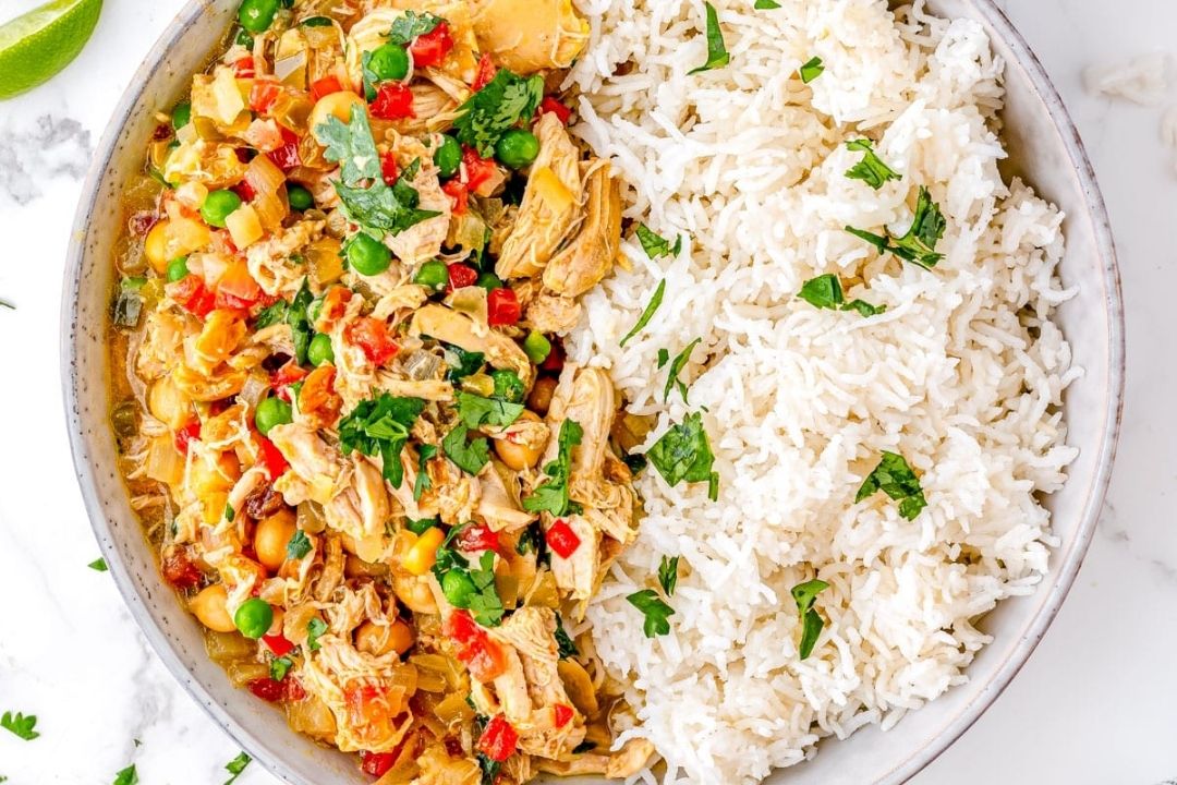 A bowl with half white rice and half shredded chicken mixed with vegetables and herbs, garnished with chopped cilantro—perfect for those looking for cozy fall recipes or easy Crockpot recipes.