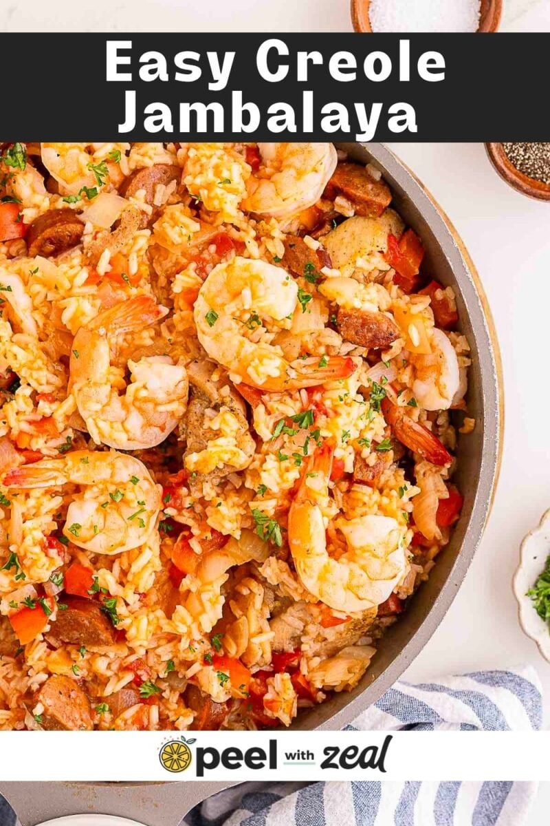 A skillet filled with creole jambalaya containing rice, shrimp, sausage, and vegetables, garnished with herbs.