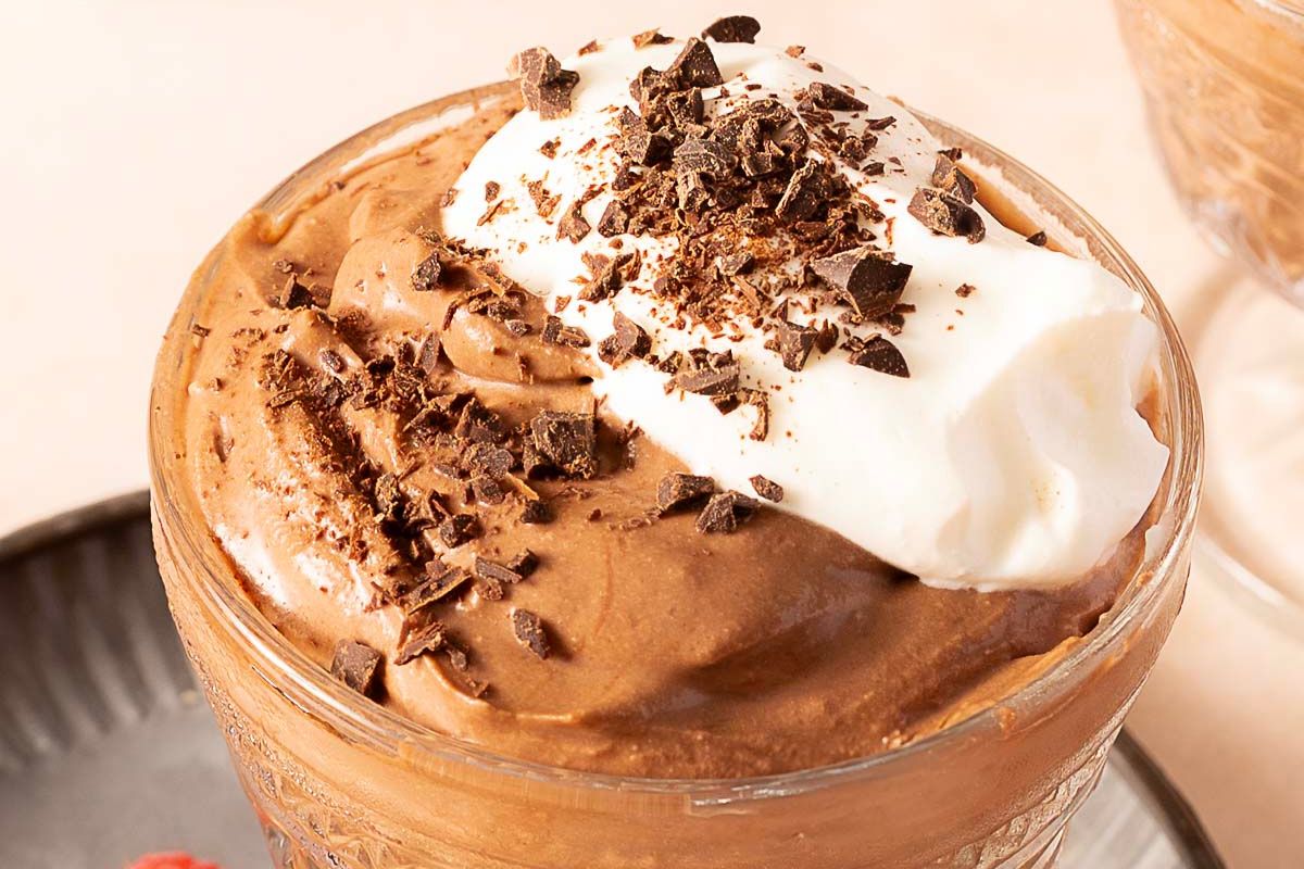 A glass cup filled with chocolate mousse, topped with a dollop of whipped cream and sprinkled with chocolate shavings—this is a must-try for chocolate lovers searching for decadent dessert recipes.