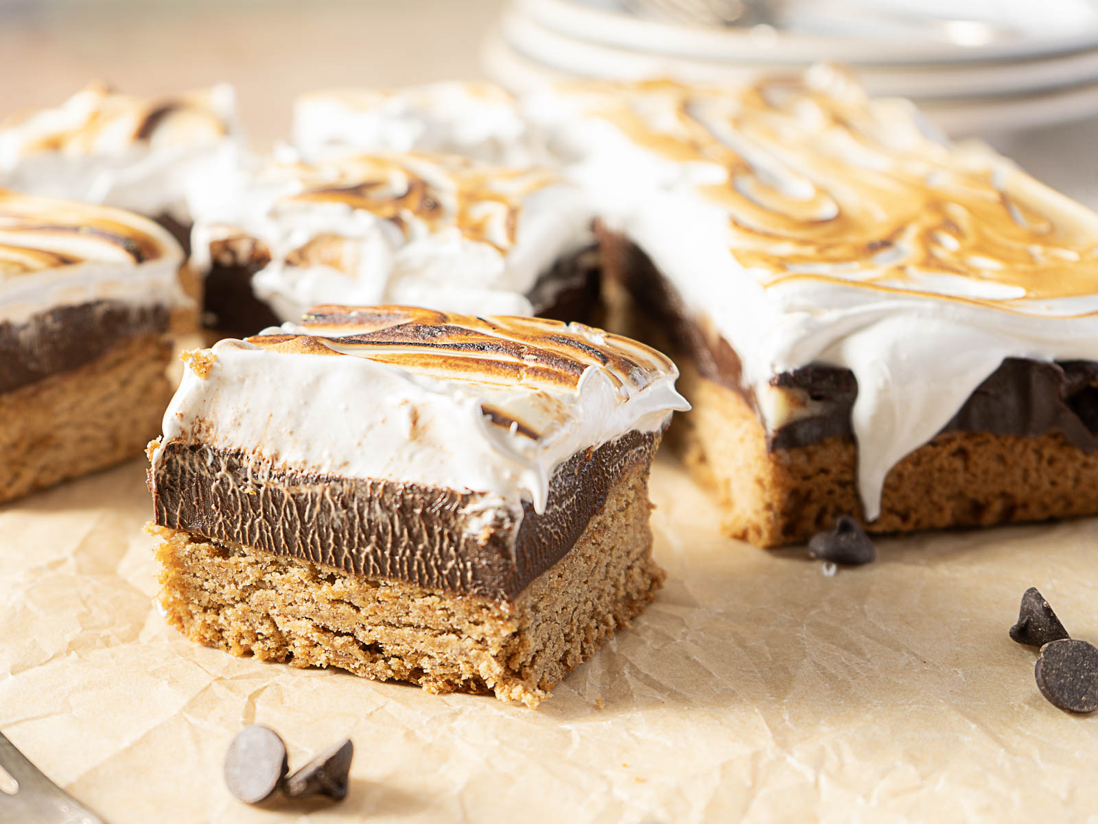 A close-up of chocolate and marshmallow bars on a piece of parchment paper, with chocolate chips scattered nearby—perfect for adding to your collection of gluten-free Labor Day recipes.