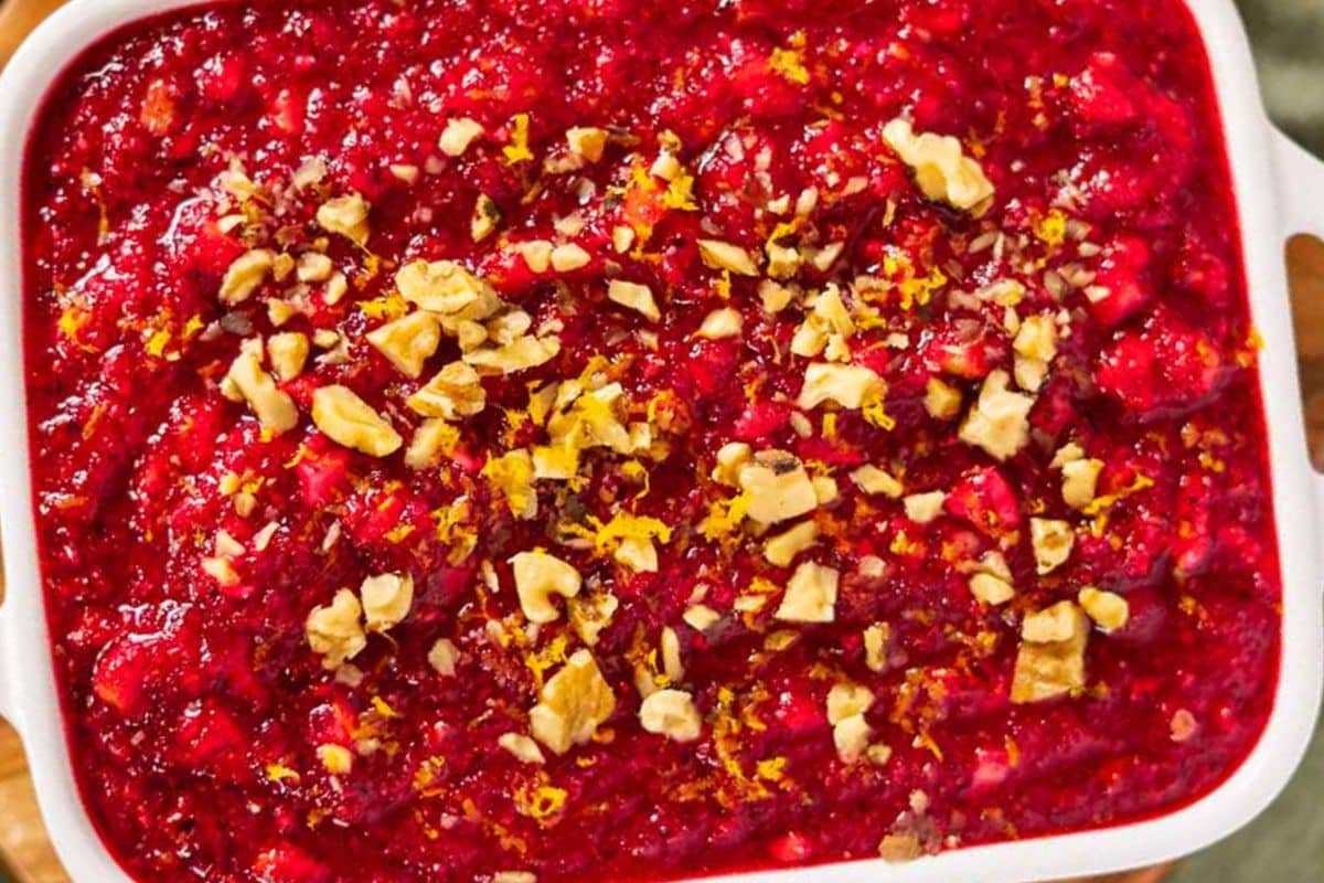 A square dish filled with cranberry relish, topped with chopped walnuts and orange zest—one of the ultimate potluck salads that’s perfect for parties or gatherings.