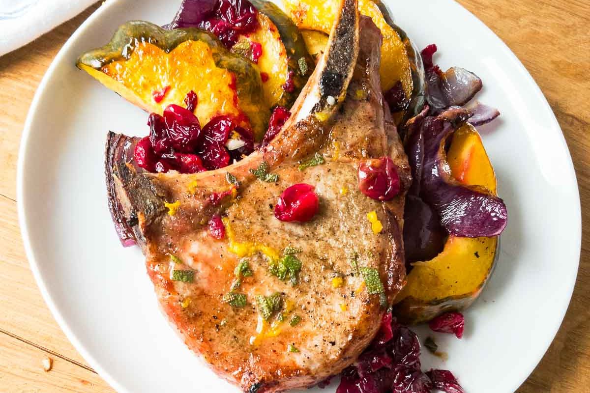 Grilled pork chop served with roasted acorn squash, cranberries, and red onions on a white plate—perfect for easy dinner or weeknight meals.