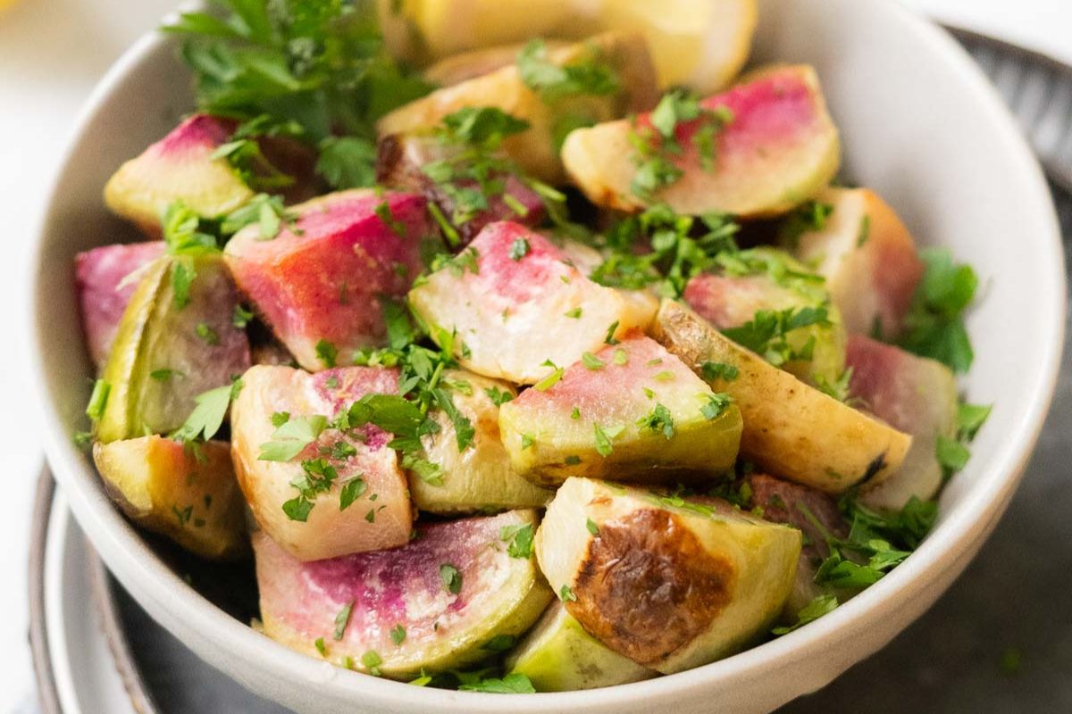 A white bowl filled with roasted chunks of watermelon radish and Brussels sprouts, garnished with chopped parsley—a vibrant addition to any collection of easy vegetable dishes or vegetarian recipes.