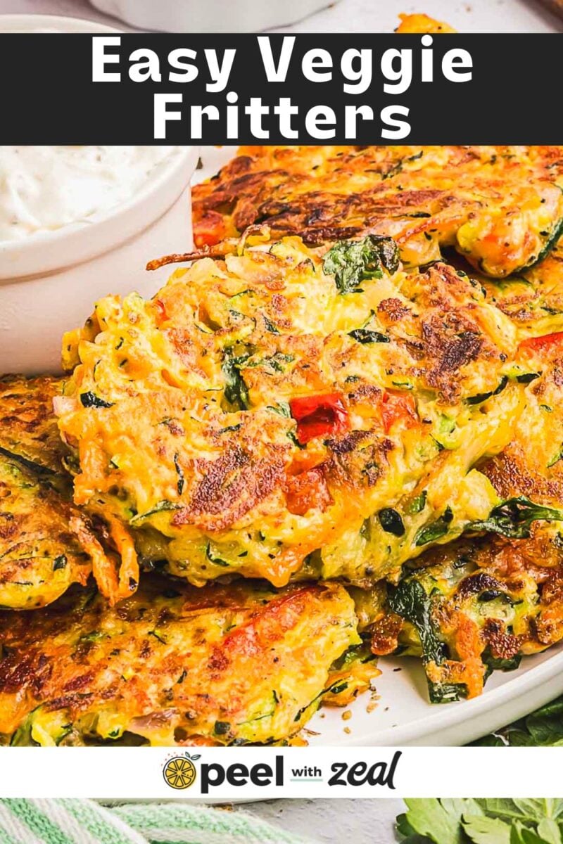 A plate of golden-brown vegetable fritters garnished with herbs, served with a side of flavorful garlic sauce.
