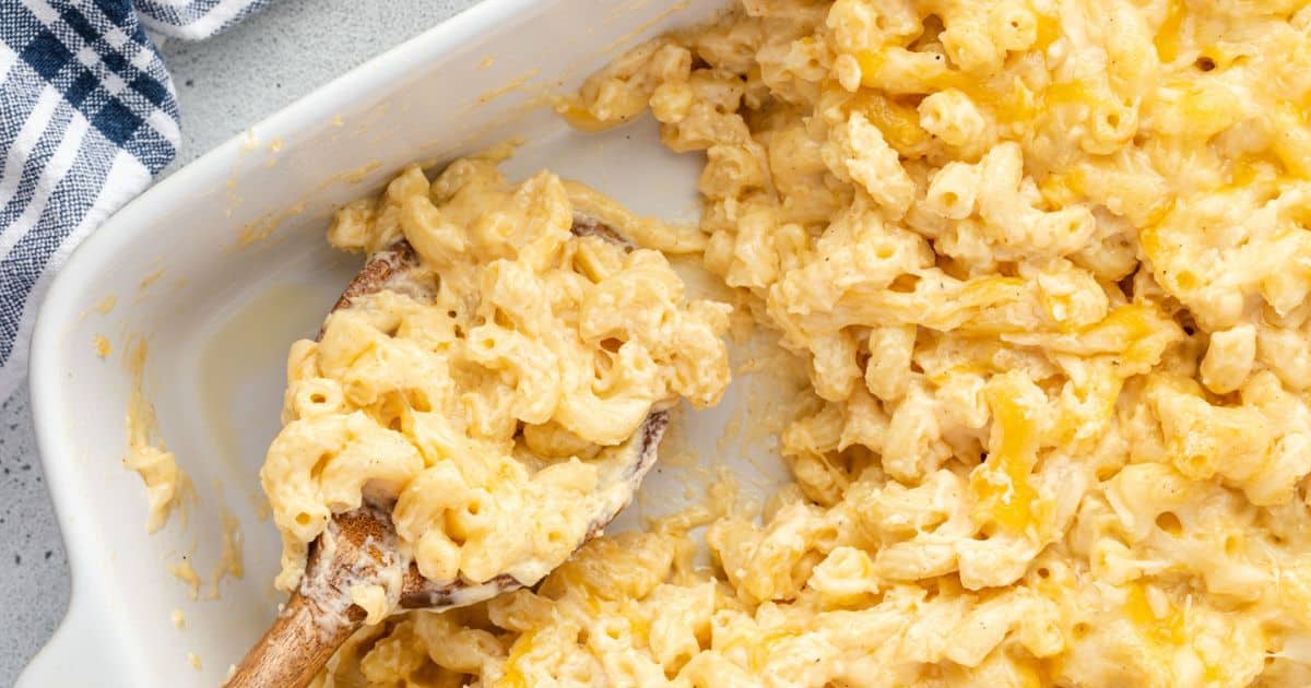 Baked macaroni and cheese in a white dish, with a wooden spoon scooping out a portion—one of those classic recipes that every home cook should master.
