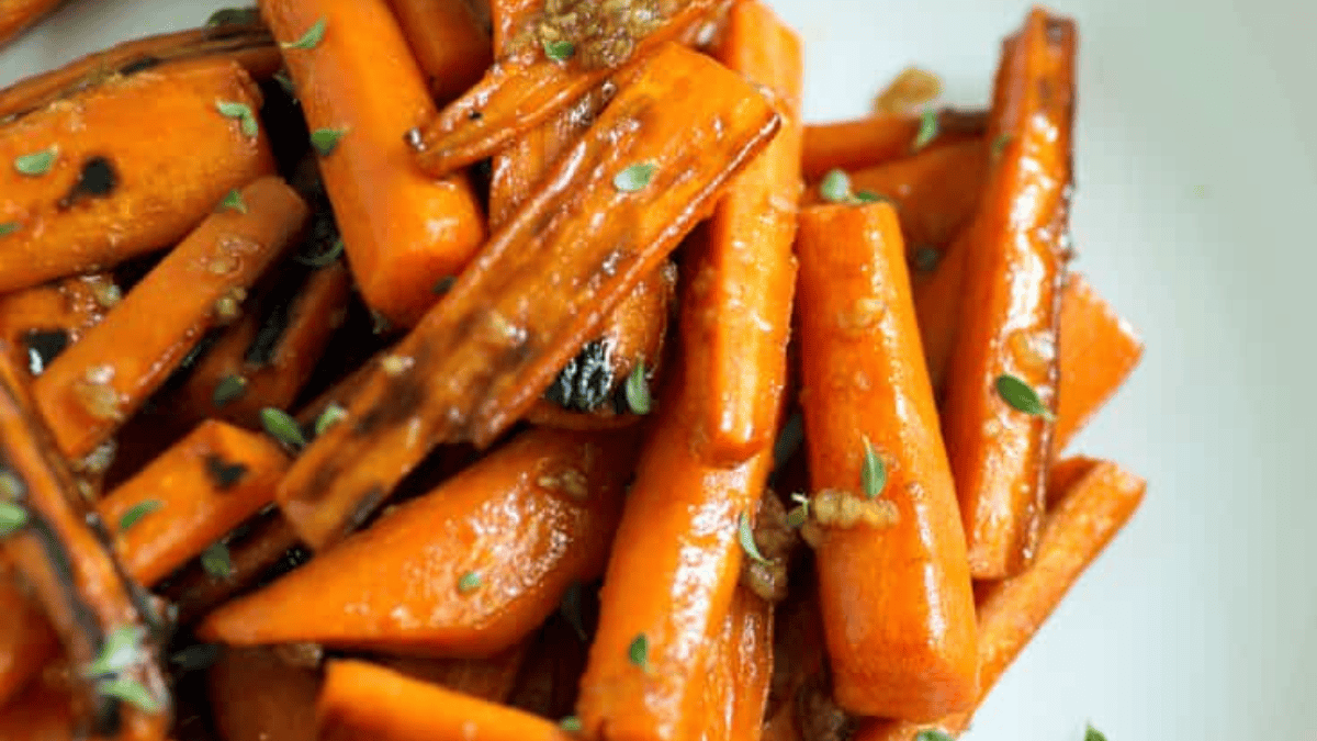 Close-up of roasted carrot sticks on a white plate, topped with herbs and a light glaze—perfect for easy carrot recipes or quick carrot sides.