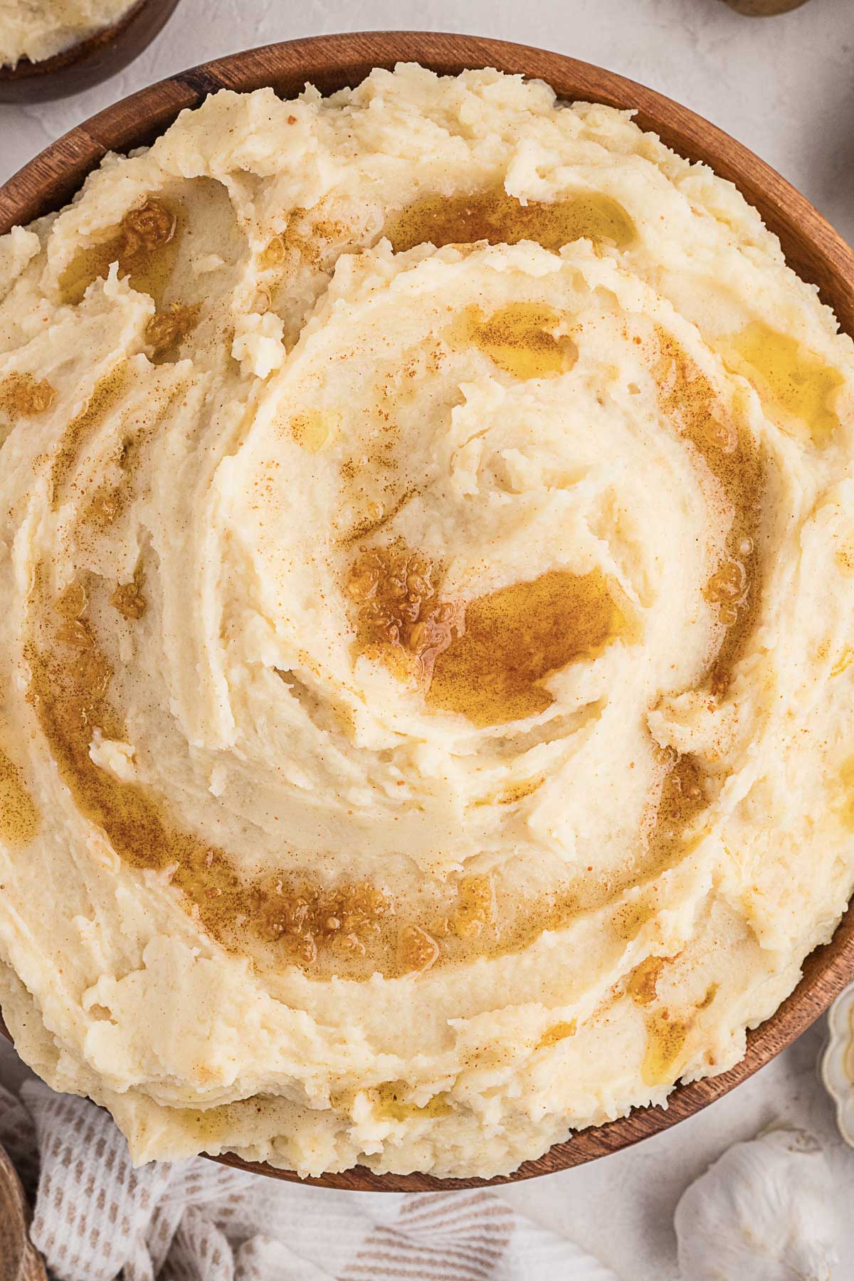 A bowl of mashed potatoes topped with melted butter, photographed from above.