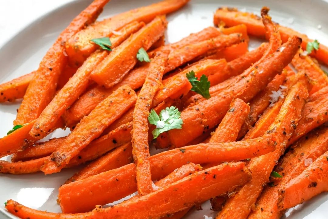 Plate of roasted carrot sticks seasoned with spices and garnished with parsley—perfect for easy carrot recipes or quick carrot sides.