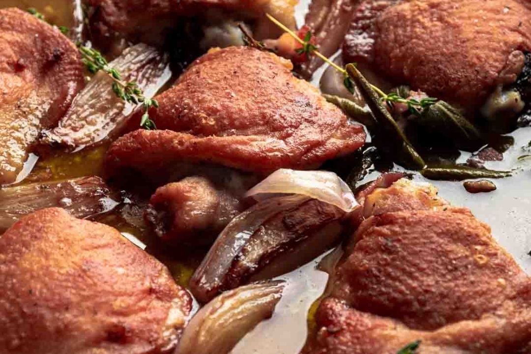 Close-up of roasted chicken thighs with crispy skin, shallots, herbs, and pan juices—a perfect comfort food for easy Sunday night recipes.