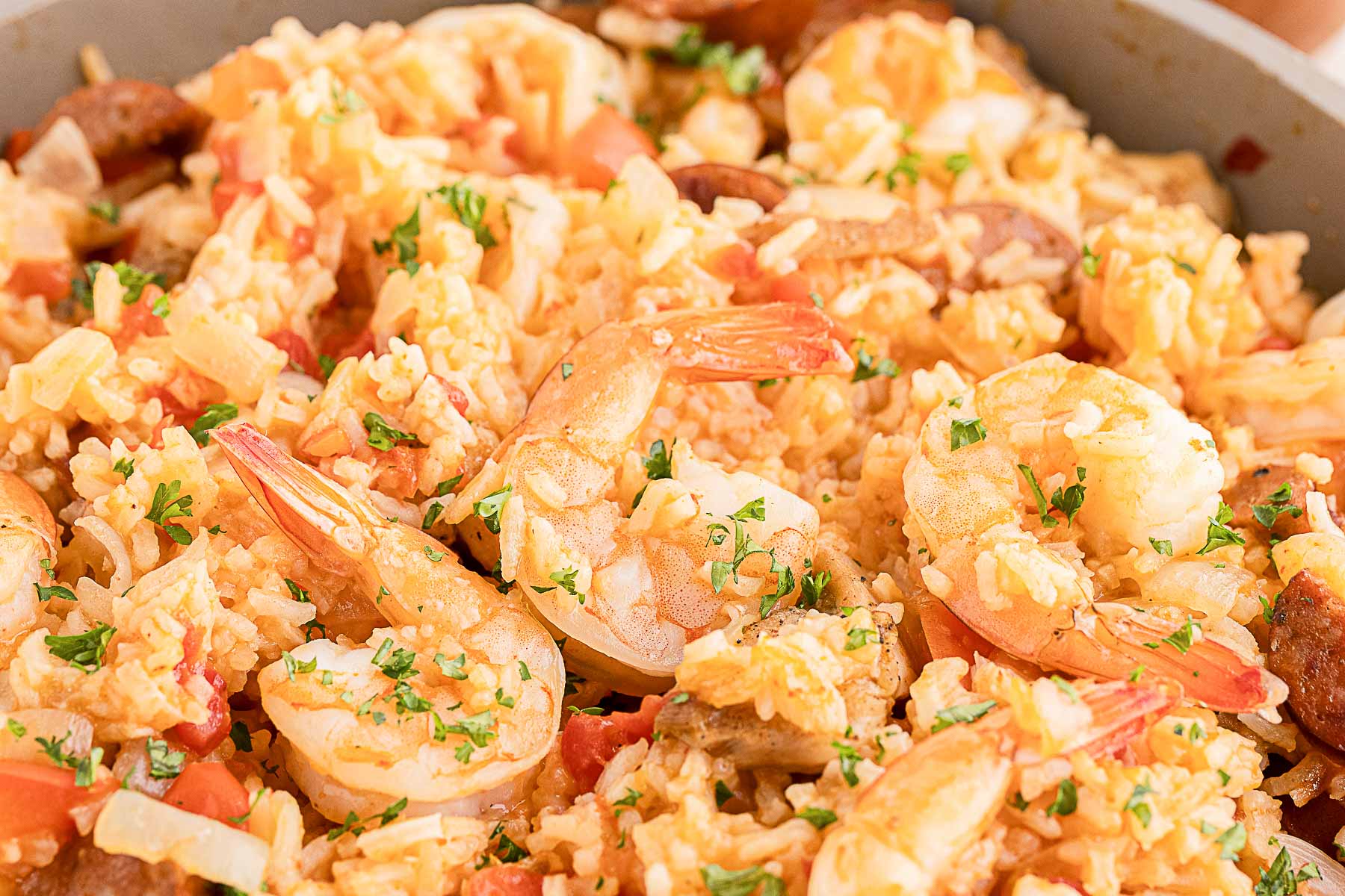 A close-up of a dish containing shrimp, rice, sausage, tomato, and chopped herbs—a true Southern Supers classic.