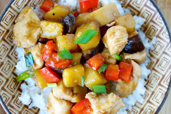 A bowl of rice topped with chunks of chicken, red bell pepper, pineapple, green onions, and a glossy brown sauce—perfect for easy dinner nights or quick weeknight meals.