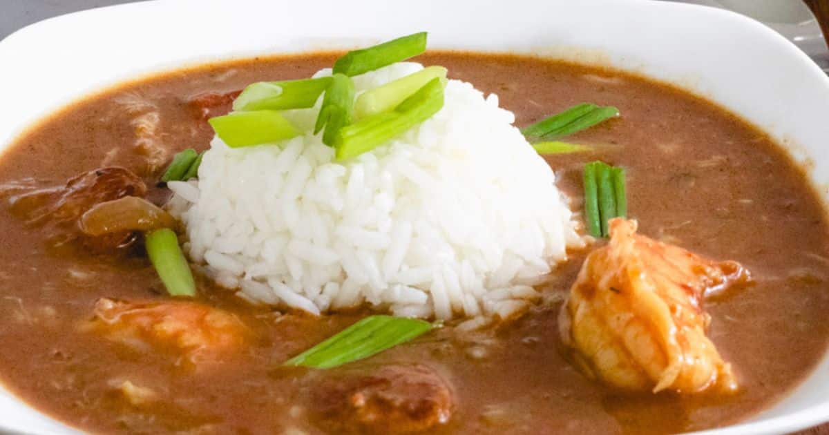 A bowl of gumbo with shrimp and sausage, served with a mound of white rice in the center and garnished with chopped green onions—one of those classic recipes that’s essential to learn for any home cook.