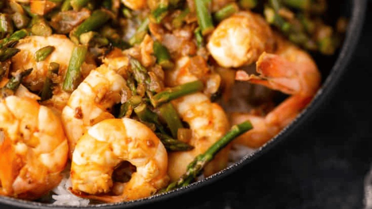 Close-up of a flavorful rice dish with cooked shrimp, chopped asparagus, and rice, all seasoned and mixed together in a pan—perfect for those who enjoy simple rice recipes.