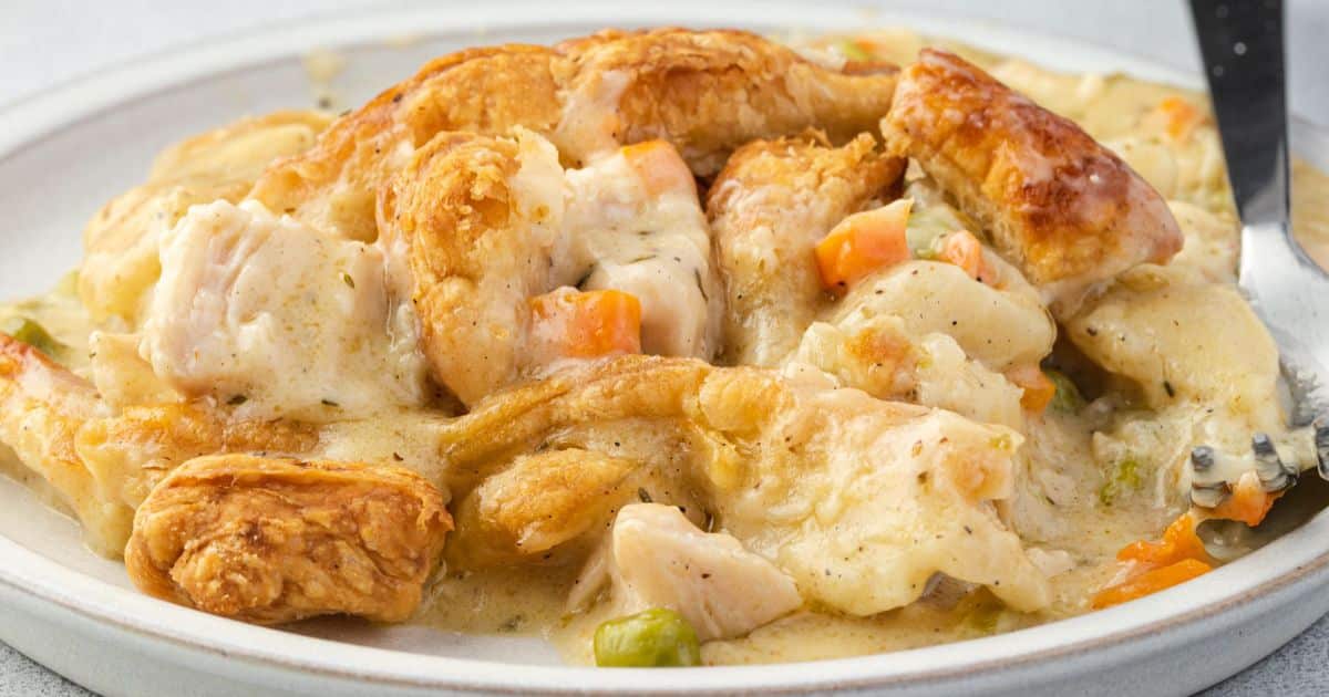A plate of chicken pot pie topped with golden, flaky pastry, filled with chunks of chicken, carrots, peas, and creamy sauce—perfect for adding comfort to your dinner routine.